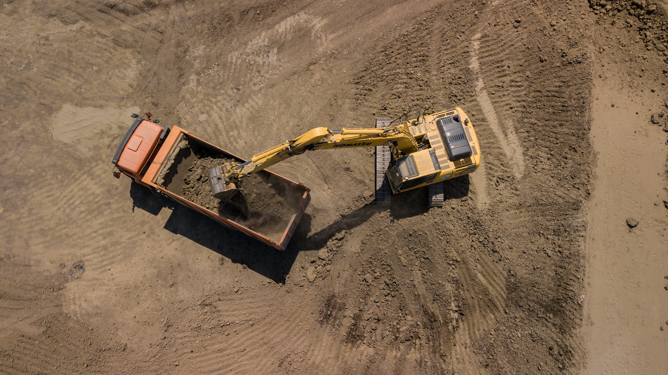 Aerial photo of excavator pours sand into the truck